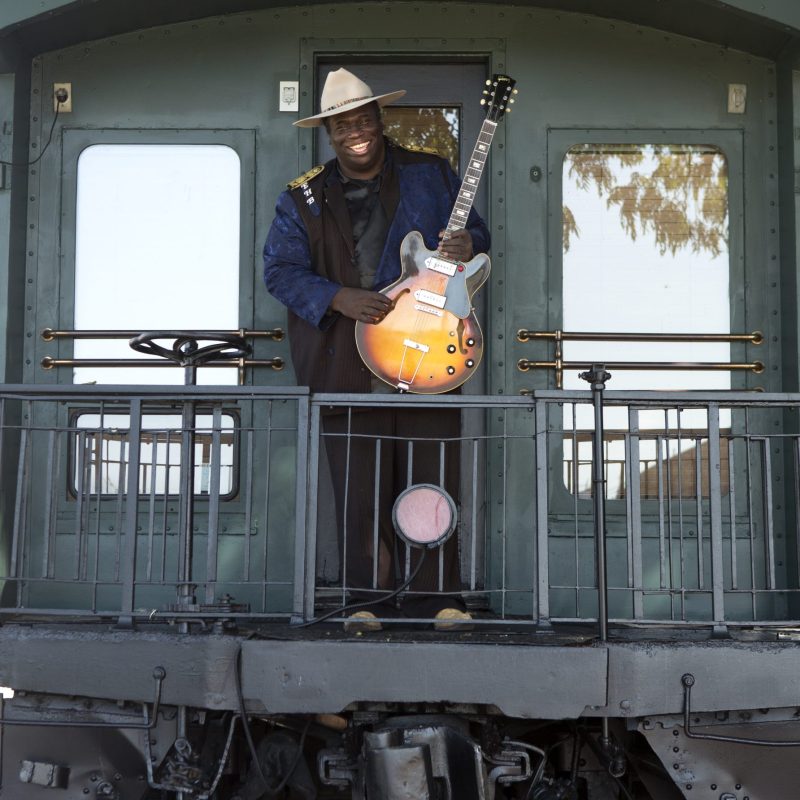 Eugene on baclk of train outside with guitar